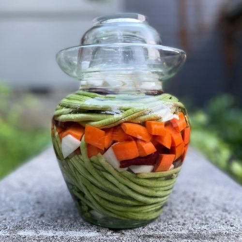 Glas mit buntem Sommergemüse in einer klaren Lake